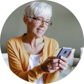 A woman smiling while looking up information on her phone.